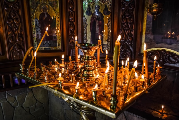 Burning candles on a stand near the icons in the chapel Attributes of Orthodox Christianity
