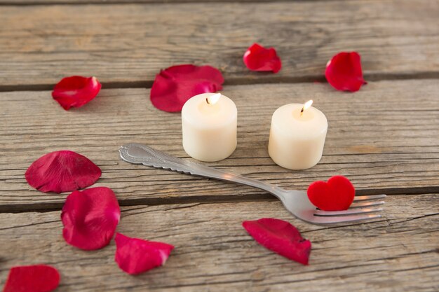 Burning candles surrounded by aromatic rose petals and fork