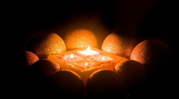 Burning candles surrounded by shiny balls on a dark background