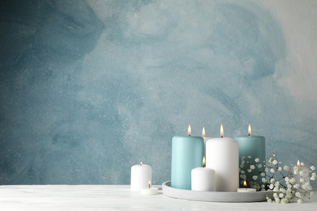 Burning candles, tray and flower on blue