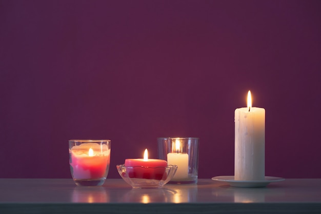 Burning candles on violet background