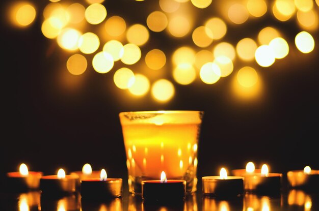 Burning candles with festive bokeh on a black background. Holiday concept. concept of prayer, hope