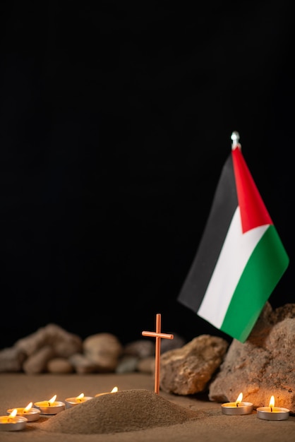 Burning candles with palestinian flag around little grave