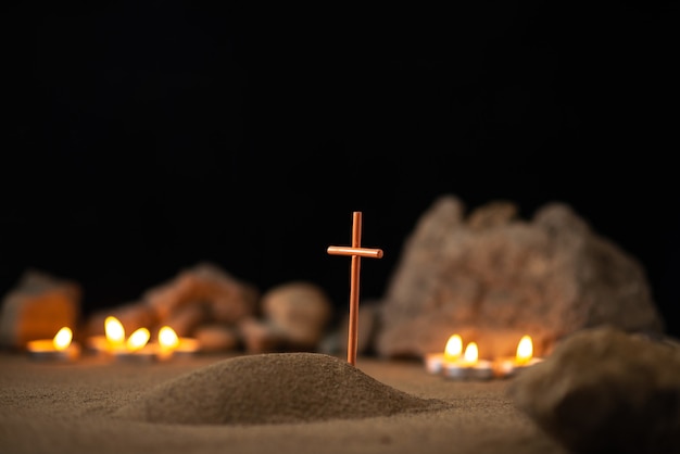 Burning candles with stones and little grave on sand as memory funeral death