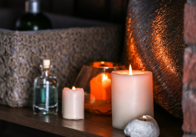 Burning candles on wooden shelf