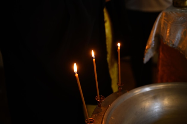 Photo burning church candles in a gilded candlestick in a temple in the dark