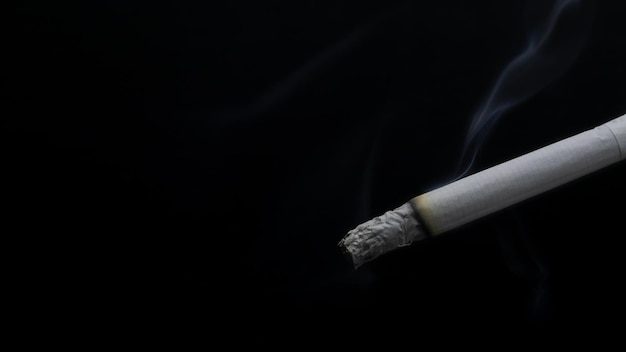 burning cigarette with smoke on black background