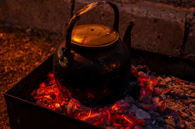 burning coals to boil water during camping and metal stove on picnic