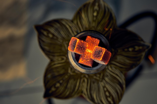 Burning coals in a bowl with hookah tobacco. Close-up, selective focus.