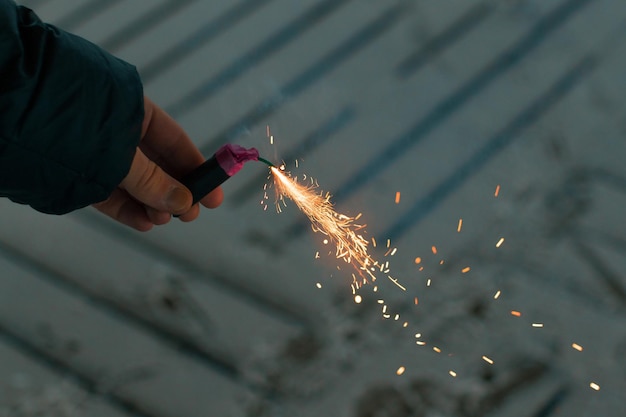 Burning firecracker with sparks guy holding a petard in a hand