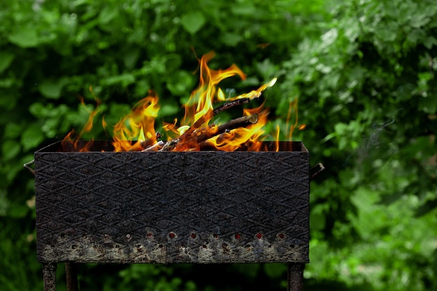 Burning firewood in a brazier in the garden with yellow fire flames outdoors