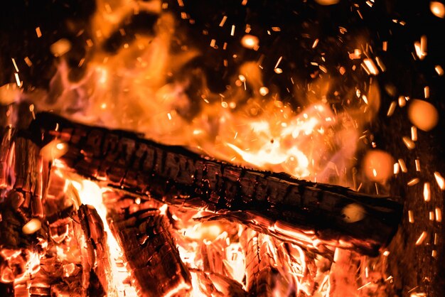 Legna da ardere in un fuoco con scintille nel buio fiamma arancione brillante