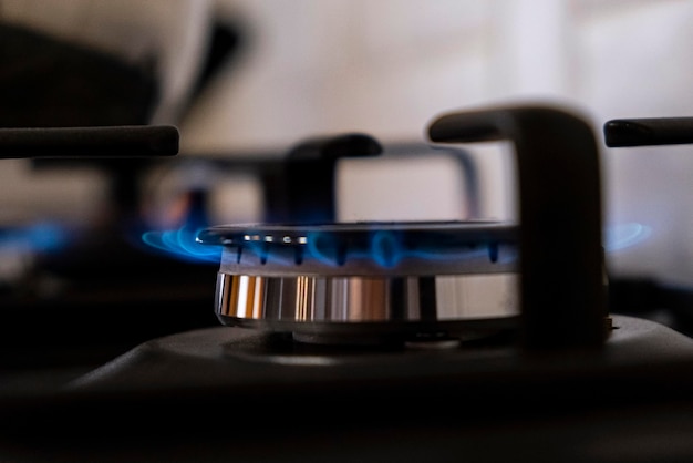 Burning gas burner with blue flames on kitchen black gas stove with a bokeh effect gasoline