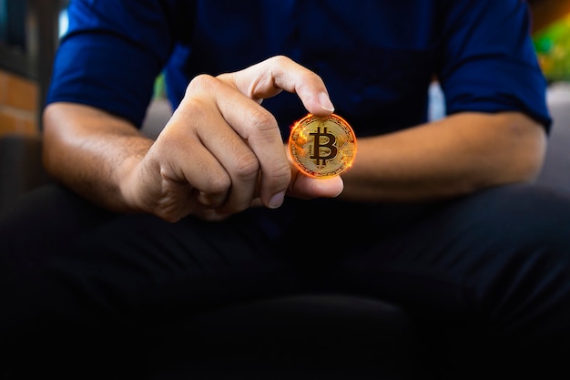 Bitcoin dorato bruciante in una mano dell'uomo d'affari nell'ufficio