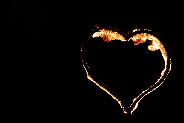 Photo burning heart with flames isolated on dark background fire show in night happy valentines day card bengal fire burning heart space for text wedding or valentine concept happy new year