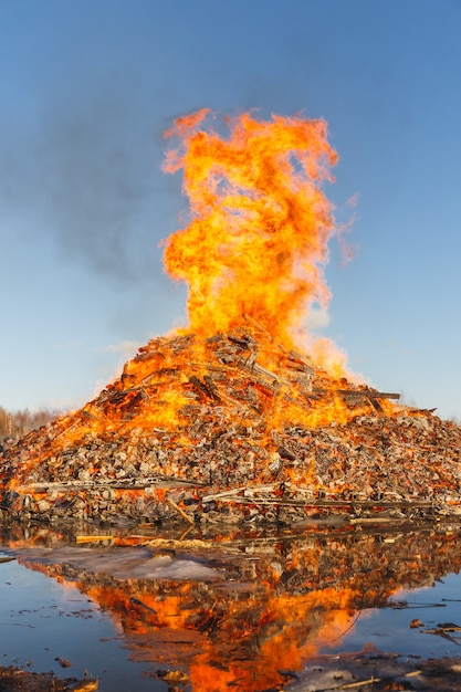 Burning huge bonfire against the blue sky