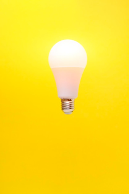 Burning LED eco friendly light bulb on yellow background