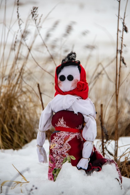 Burning maslenitsa doll on snow in the dried grass