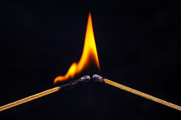 黒い背景に燃えているマッチ火の炎からの熱と光