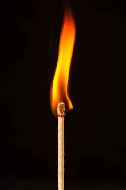 Burning matchstick on black background