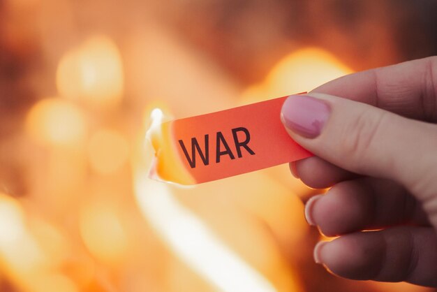 Burning paper in hands of a woman with word war Concept of horrors of war Thousands of killed people destructed homes other awful things it brings