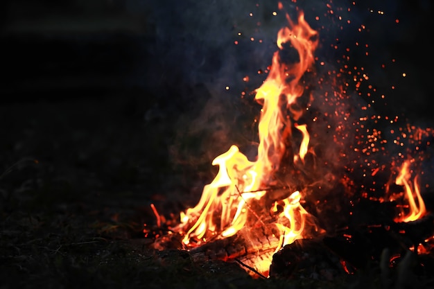 Scintille roventi che bruciano volano da un grande fuoco carboni ardenti particelle fiammeggianti che volano via contro