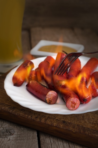 Photo burning sausages on plate with mustard sauce