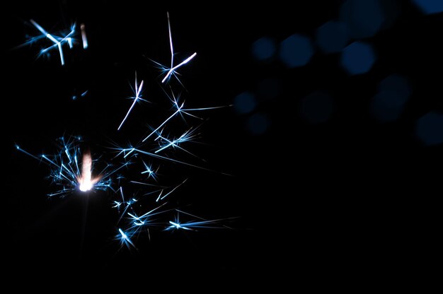 Burning sparkler in blue and white light on a black background Closeup photo of Christmas and new year sparkler Can be used like a wallpaper or postcard