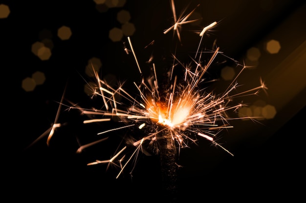 Burning sparkler in yellow and orange light on a black background Closeup photo of Christmas and new year sparkler Can be used like a wallpaper or postcard