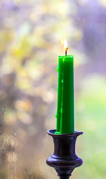 Burning wax candle in brass candlestick in country house interior.