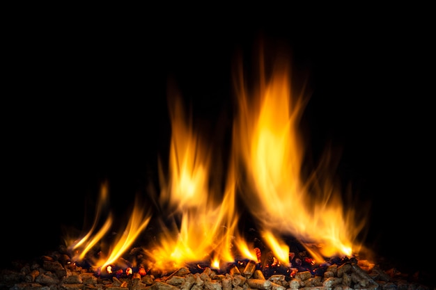 Burning wood pellets, visible flame and dark background. 