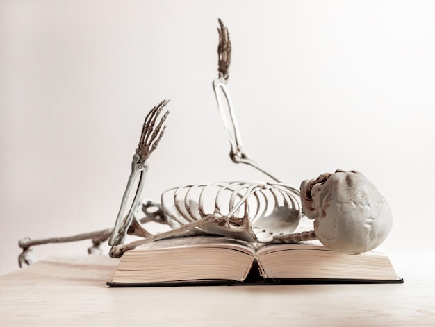 Burnout concept Tired skeleton lying over book Tiredness death exhaustion