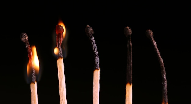 Burnt and burning matches on black background