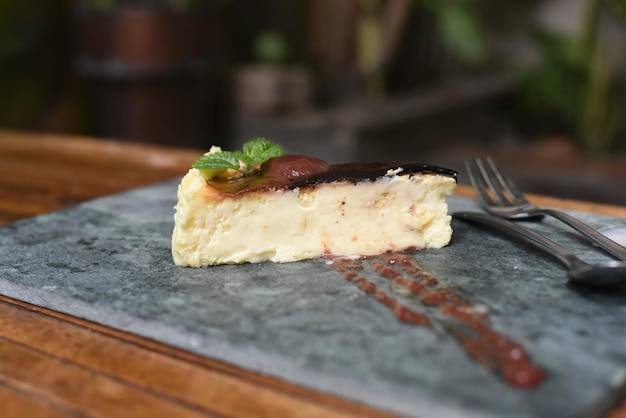 Burnt cheesecake on a stone plate with mint leaf ant toping on gray stone background top view