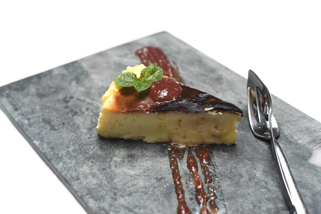 Burnt cheesecake on a stone plate with mint leaf