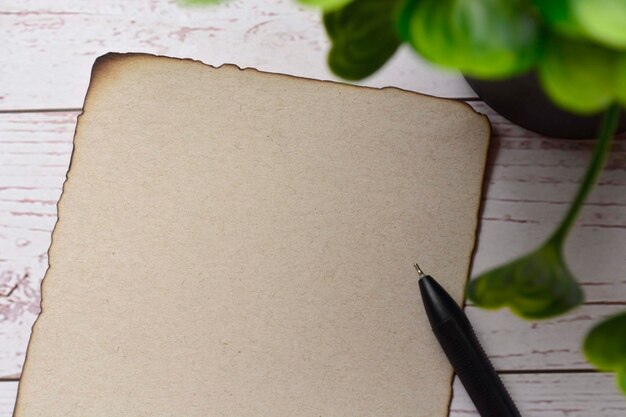 Обожженная коричневая бумага с ручкой на деревянном столе. Бланк для текста