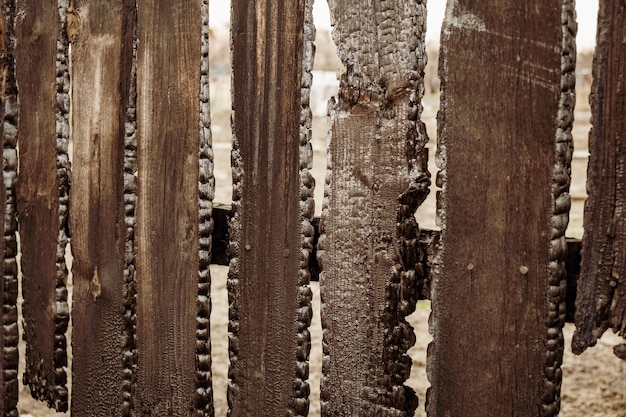 Burnt fence boards after a fire in a private house. The consequences of not careful and thoughtless handling of fire.