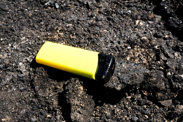 Burnt metal lighter in ashes Consequences of the fire Closeup