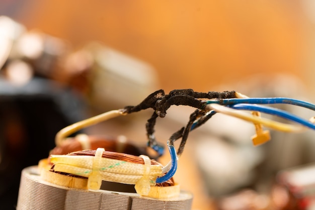 Burnt wires on the parts of an electrical appliance, drills on a wooden table in a repair shop. power tool repair