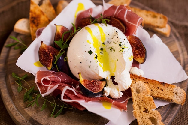 Burrata appetizer with prosciutto olive oil dried figs and toasted bread