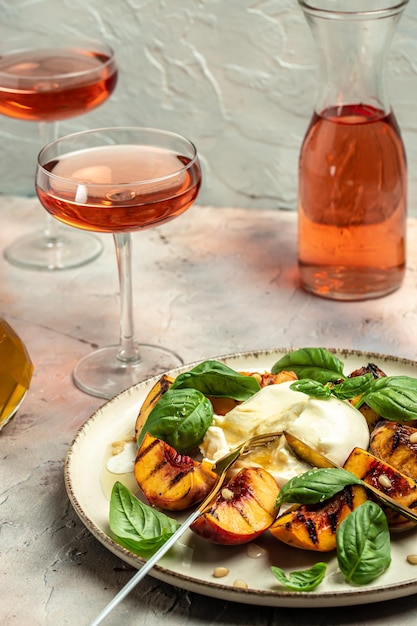 Photo burrata cheese and grilled peaches with rose wine vertical image top view place for text