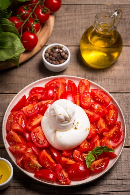 Burrata cheese salad with cherry tomatoes, olive oil and seasoning. Fresh food concept.