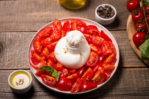 Burrata cheese salad with cherry tomatoes, olive oil and seasoning. Fresh food concept.