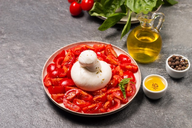 Burrata kaassalade met tomaten, olijfolie en kruiden. vers voedselconcept.