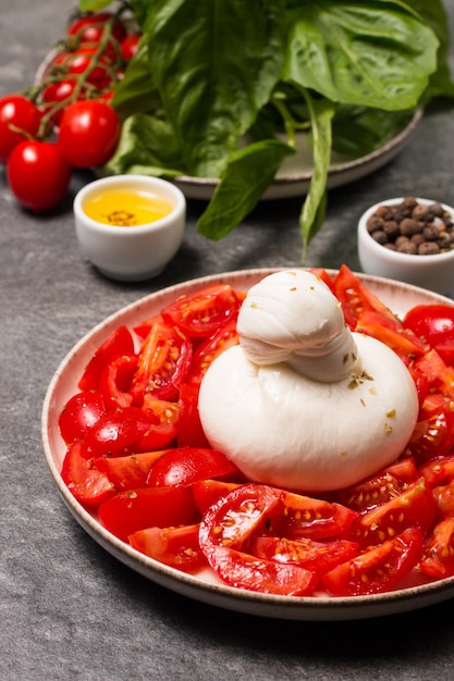 Burrata kaassalade met tomaten, olijfolie en kruiden. Vers voedselconcept.