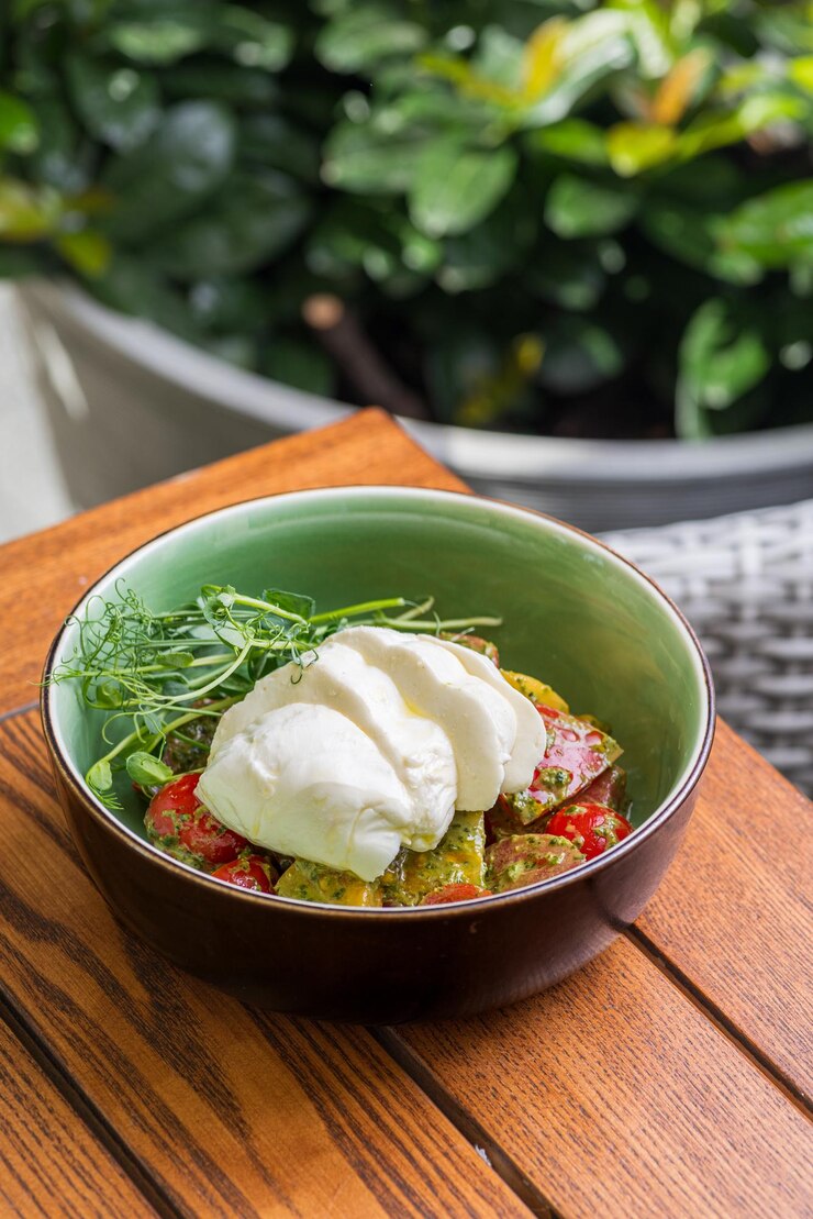 Photo burrata salad with cherry tomatoes pesto and spices in a bowl
