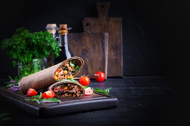 Burrito's wraps met rundvlees en groenten op donkere houten achtergrond. rundvlees burrito, mexicaans eten.