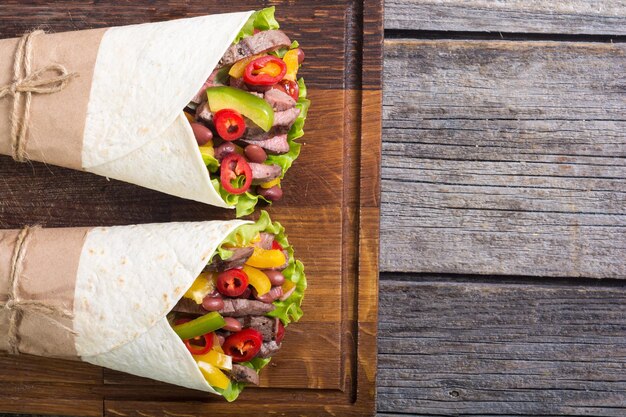 Burrito with beef salad tomato peppers and haricot food background