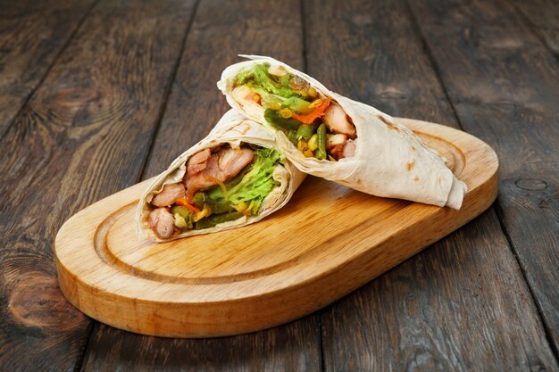 Burrito with chicken and vegetable at wooden desk