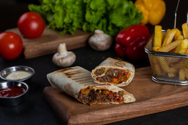 A burrito with a side of vegetables on a cutting board